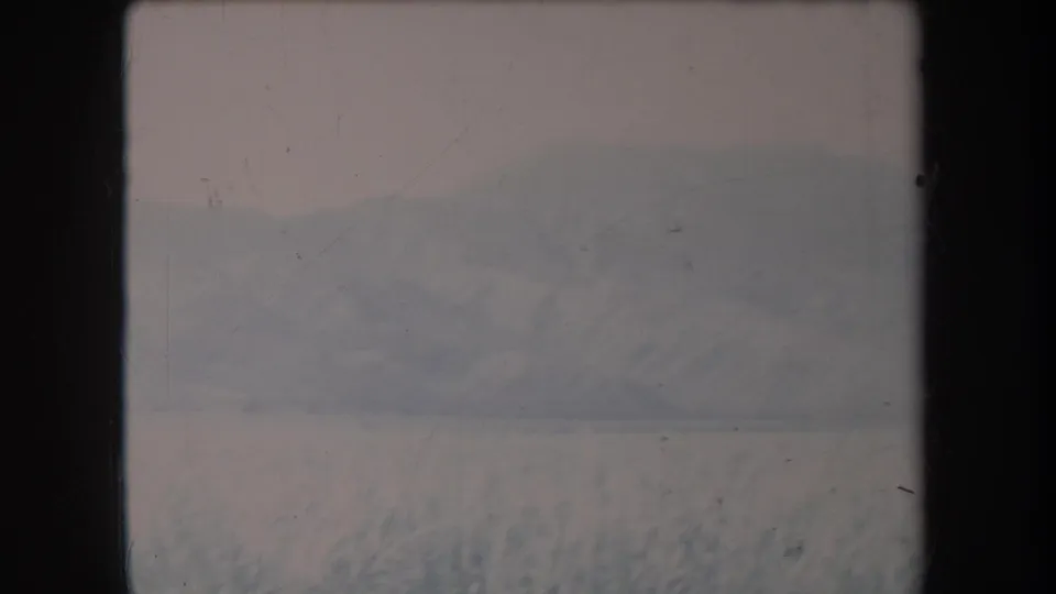1969 Hawaii home-movie frame with snow in the foreground and a faded mountain range across the horizon.