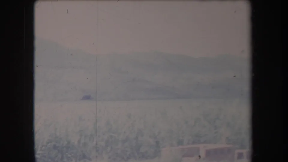 1969 Hawaii home-movie frame of a snow-covered landscape with a distant ridge and a small dark speck in the scene.