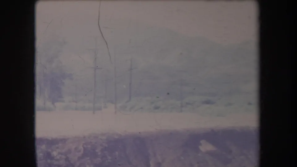 Faded 8mm Hawaii landscape showing utility poles across low greenery with hazy hills in the background and a pale foreground strip.