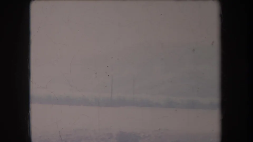 1969 Hawaii 8mm frame with a pale field, faint vegetation, distant trees, and visible film marks across the scan.