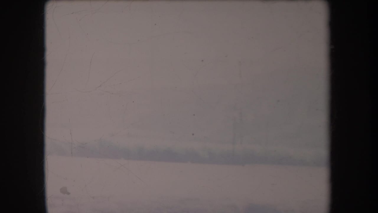 Soft 1969 Hawaii home-movie frame showing a hazy roadside landscape under an overcast sky.
