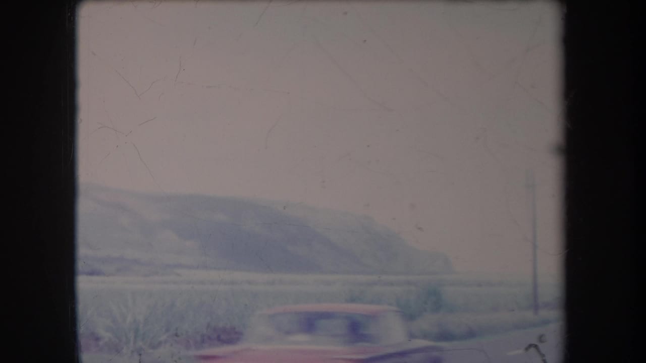 Hazy hills and low vegetation seen through a dark framed opening.