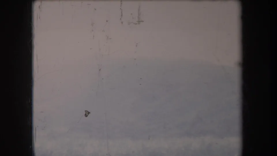 Faded 1969 Hawaii 8mm frame showing a hazy mountain slope, low vegetation, pale sky, and visible film wear.