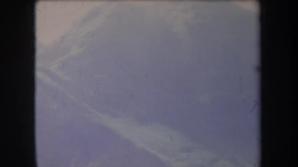 1969 Hawaii 8mm frame showing a blurred hillside against a pale sky, with soft focus, fading, and visible frame edges.