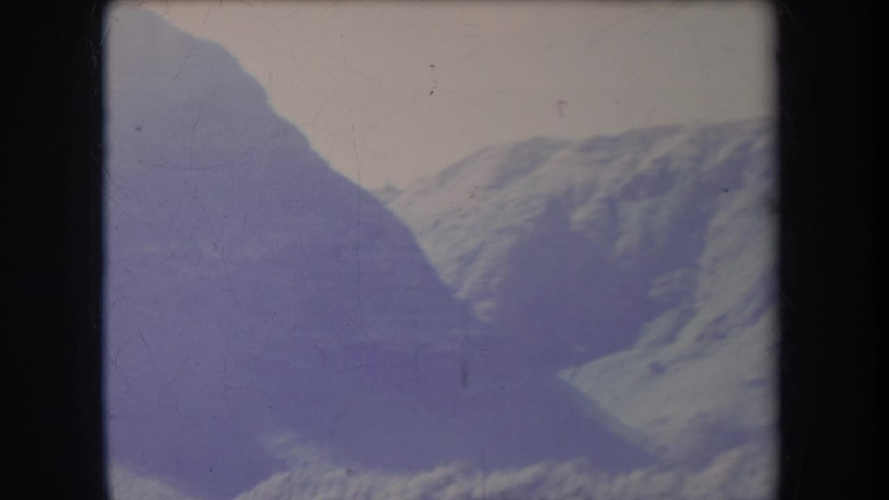 1969 Hawaii 8mm frame showing a distant treeless mountain range with shadowed slopes and a pale sky.