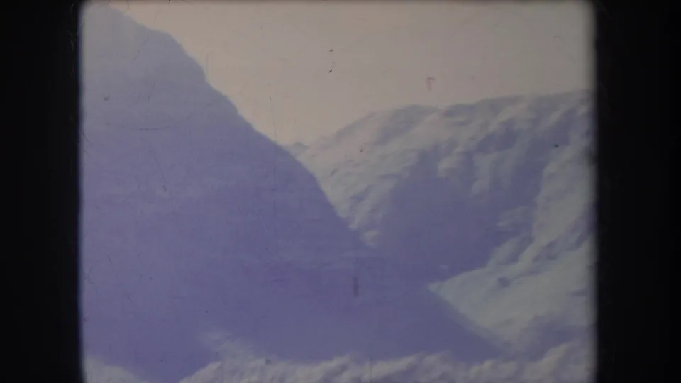 1969 Hawaii 8mm frame showing a distant treeless mountain range with shadowed slopes and a pale sky.