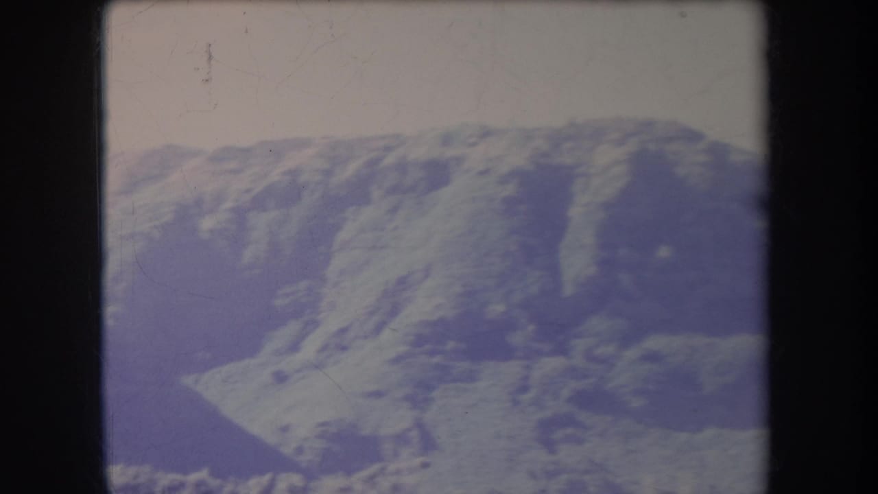 Broad mountain ridge with shadowed gullies and pale sky above.