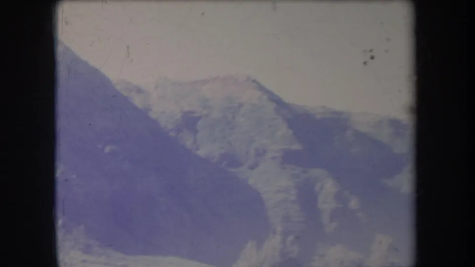 1969 Hawaii home-movie frame showing receding treeless ridges behind a dark foreground mountain slope.