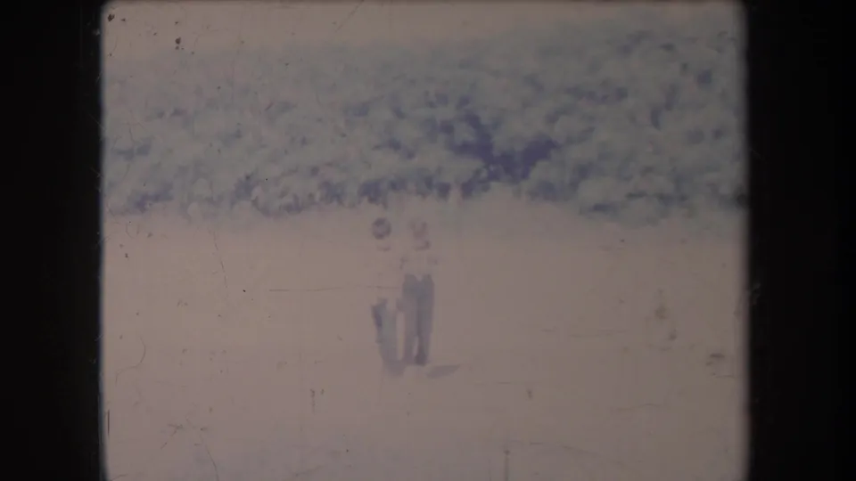 Distant figures stand or walk in a hazy Hawaii valley in 1969, with mountain terrain behind them and faded 8mm film texture.
