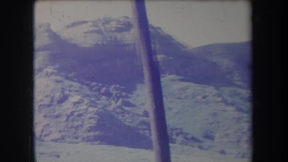 1969 Hawaii 8mm view of rugged highland terrain, snow-dusted peaks, and a vertical pole in the foreground.