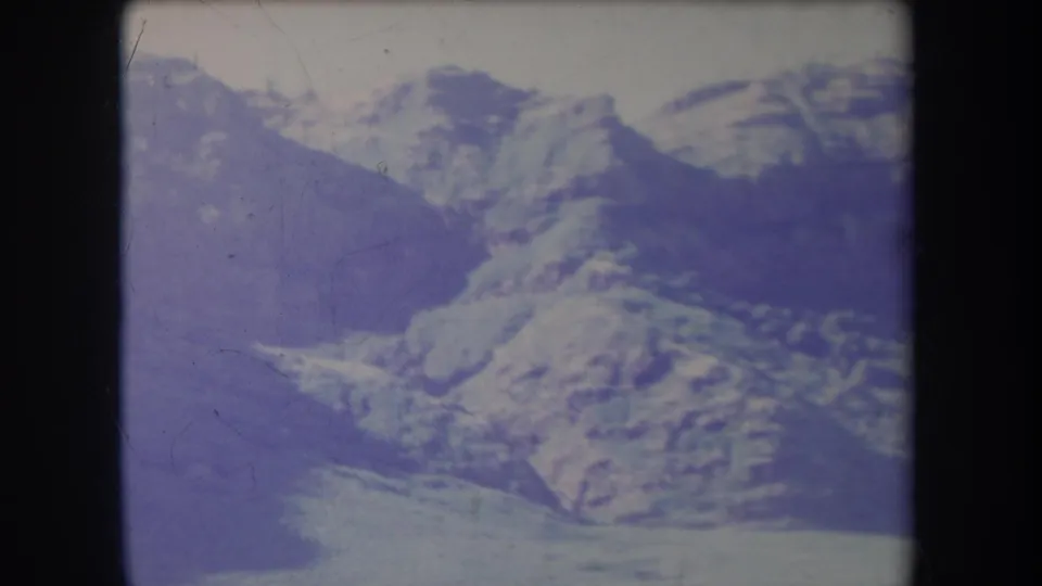 1969 Hawaii 8mm frame showing layered mountain ridges with snow patches, faded color, and soft home-movie exposure.