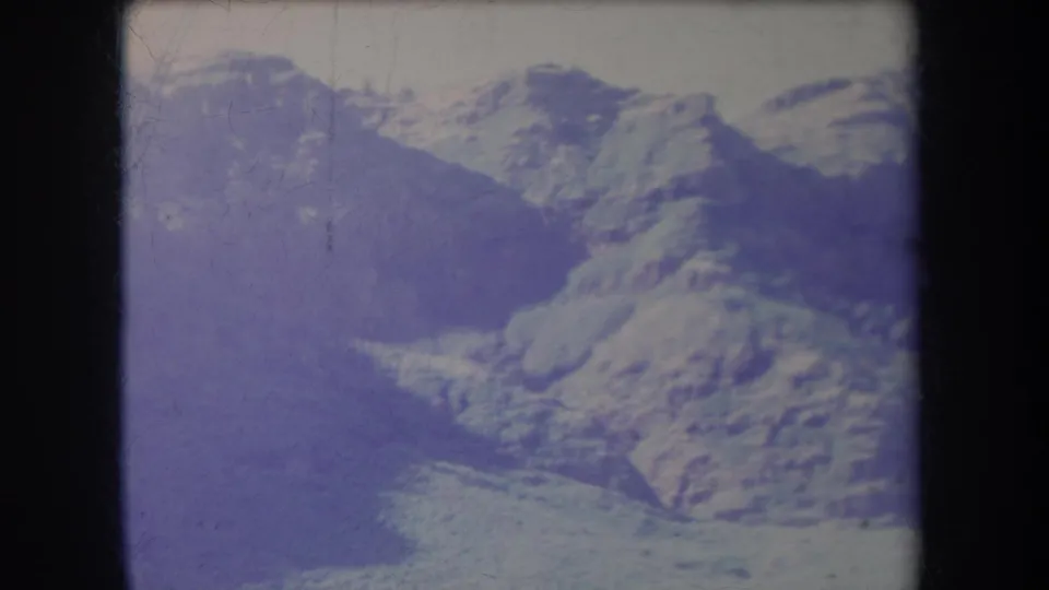 1969 Hawaii 8mm frame showing hazy mountain terrain, a distant coastline, soft focus, and visible film wear.
