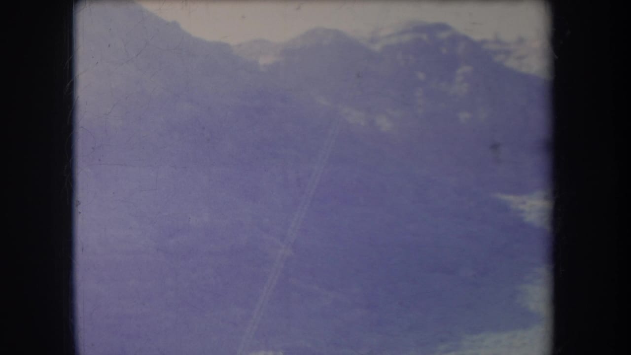 Soft purple mountain view with layered peaks and film surface marks.