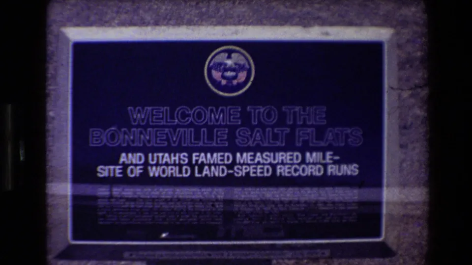 Darker 8mm frame of the Bonneville Salt Flats sign, partly crossed by a horizontal light streak near the lower text area.