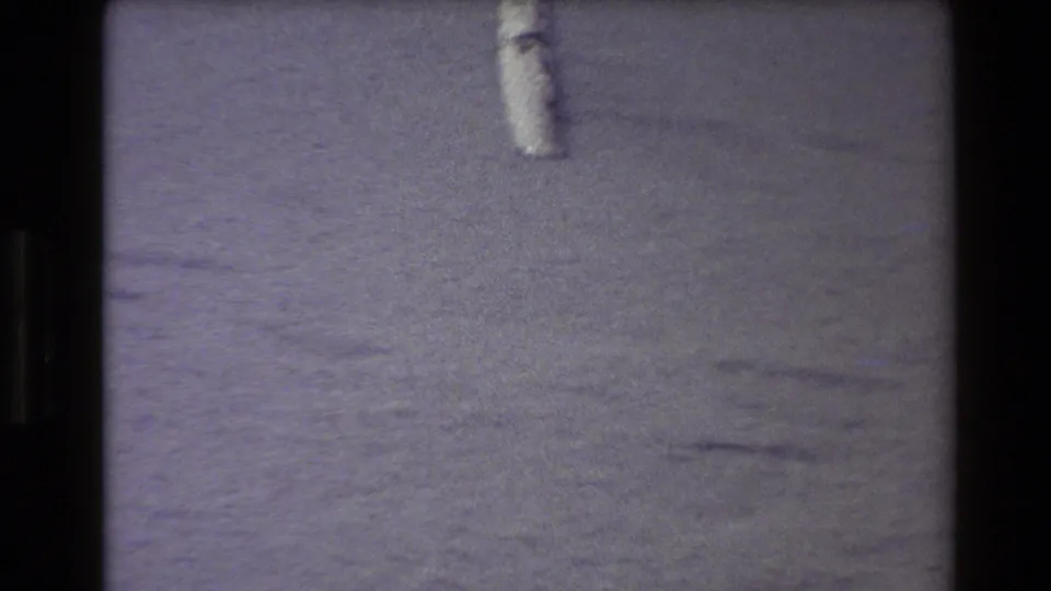 1980 Western USA 8mm frame showing a small pale object near the top edge on grainy sand with purple color shift and film-frame borders.