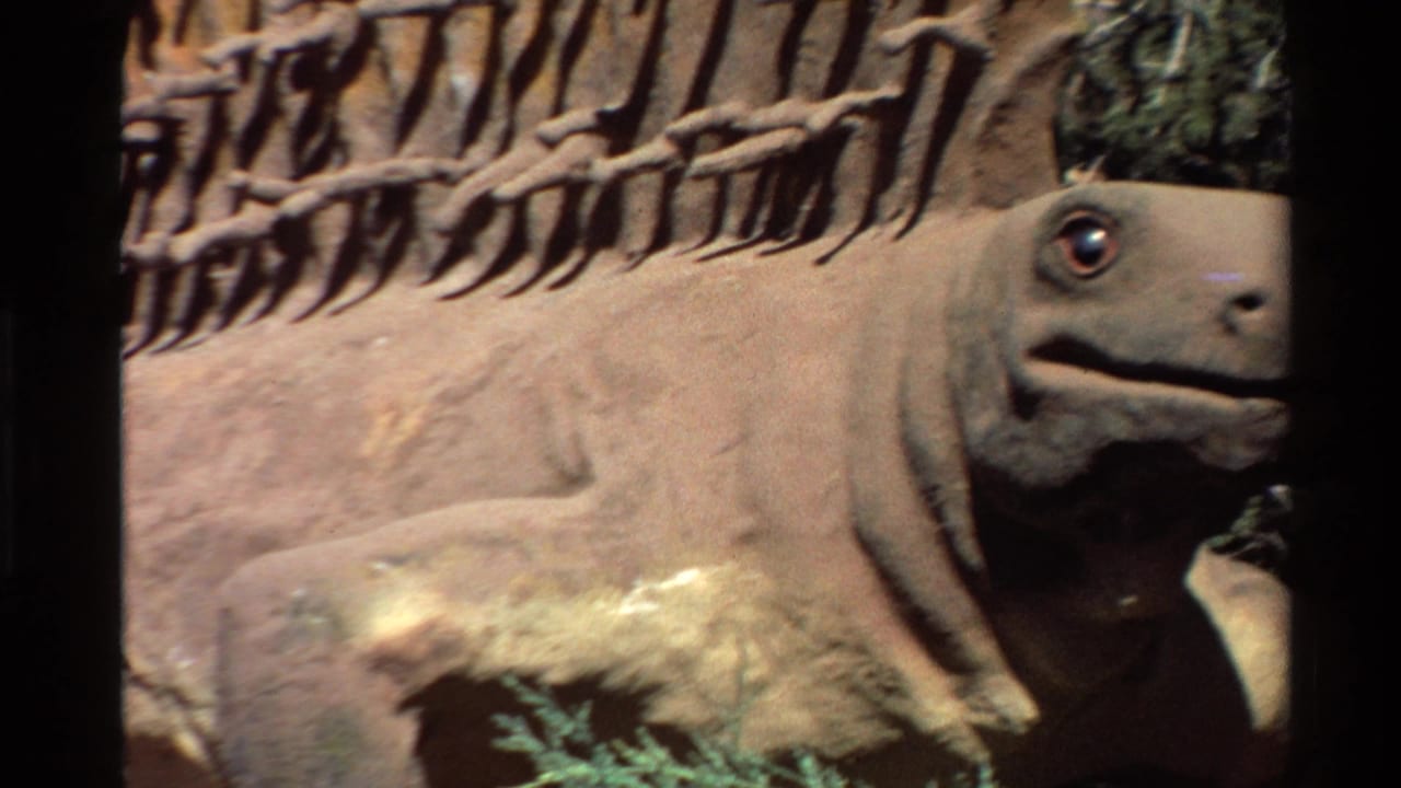 Close view of a brown prehistoric reptile statue with a red eye and spined back.