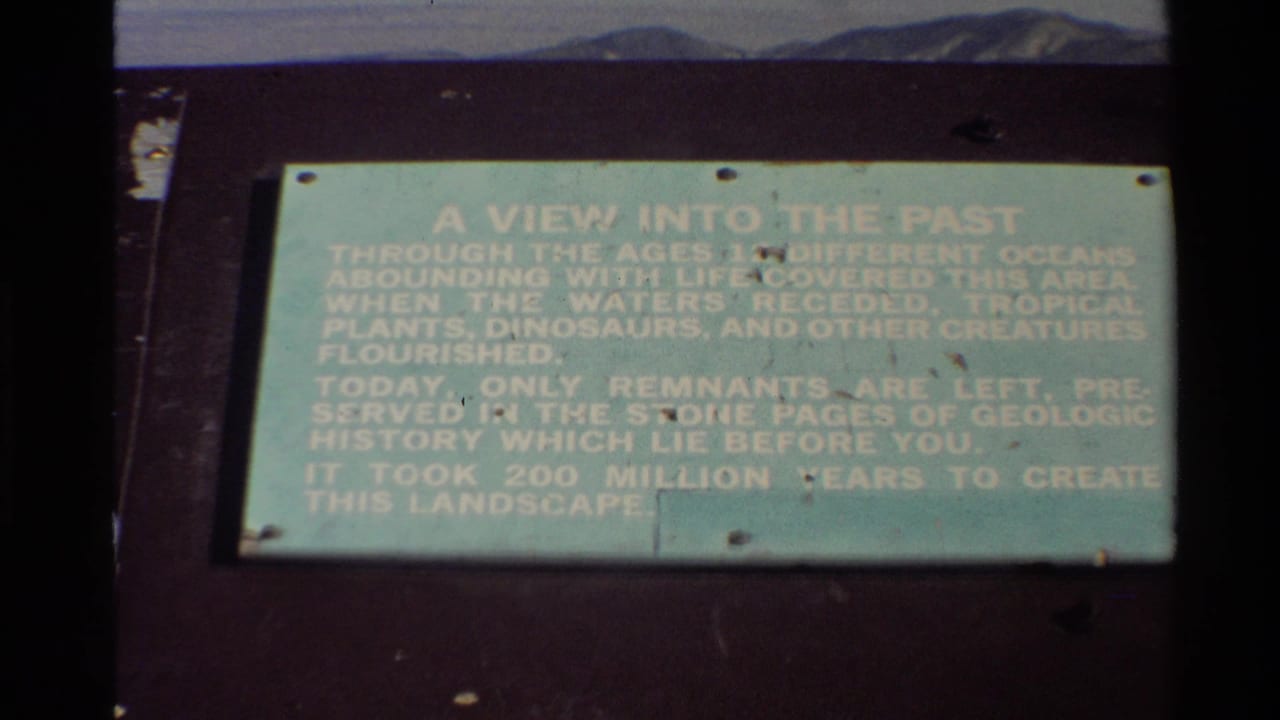 Outdoor 8mm view of a green interpretive sign describing ancient waters and landscape formation in the Western USA.