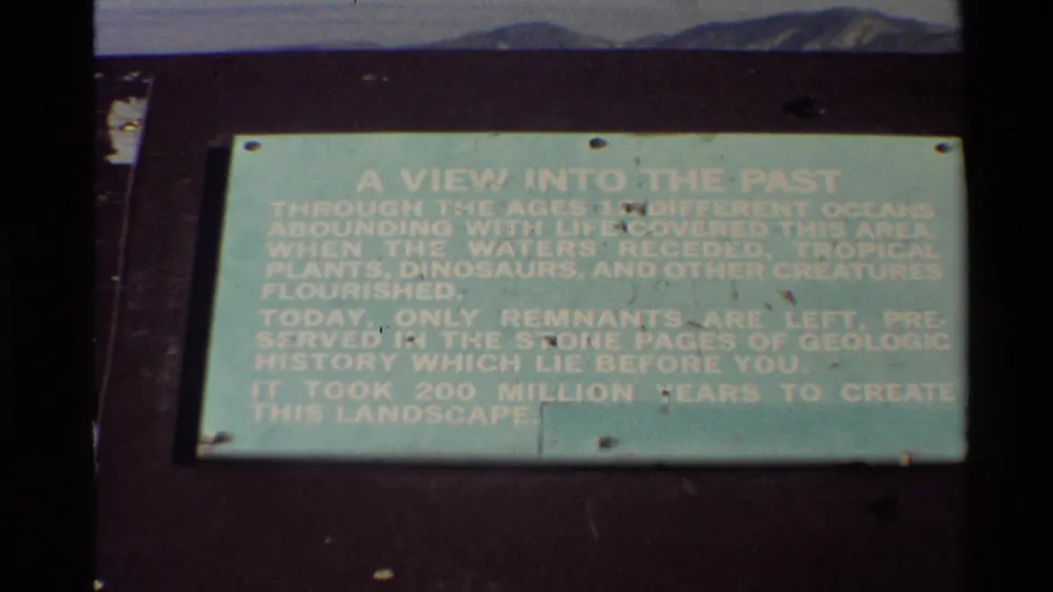 Outdoor 8mm view of a green interpretive sign describing ancient waters and landscape formation in the Western USA.