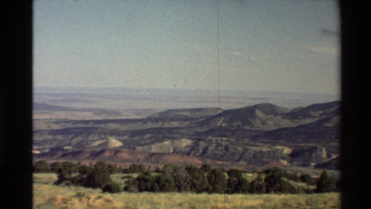 Distant mountain ridge with meadow grass and shrubs in the foreground.