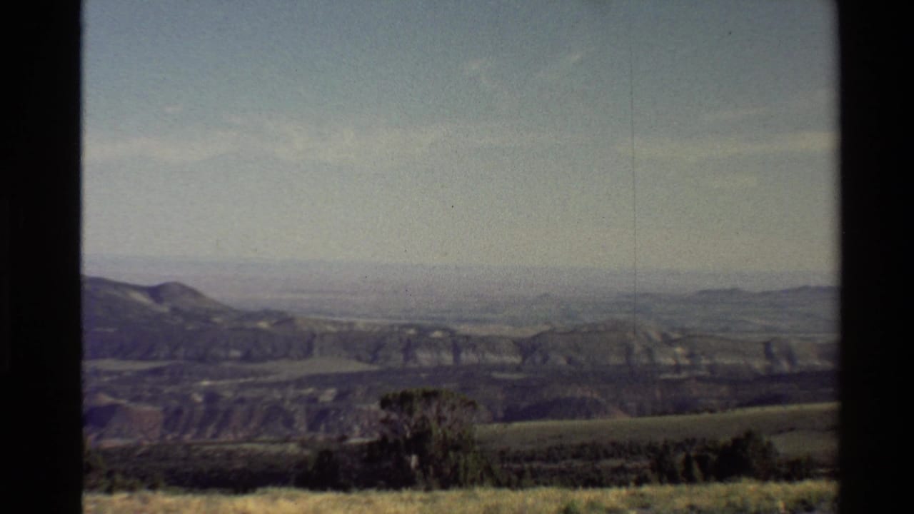 1980 Western USA home-movie still showing rolling terrain, scrub vegetation, distant ridges, and faded 8mm color.
