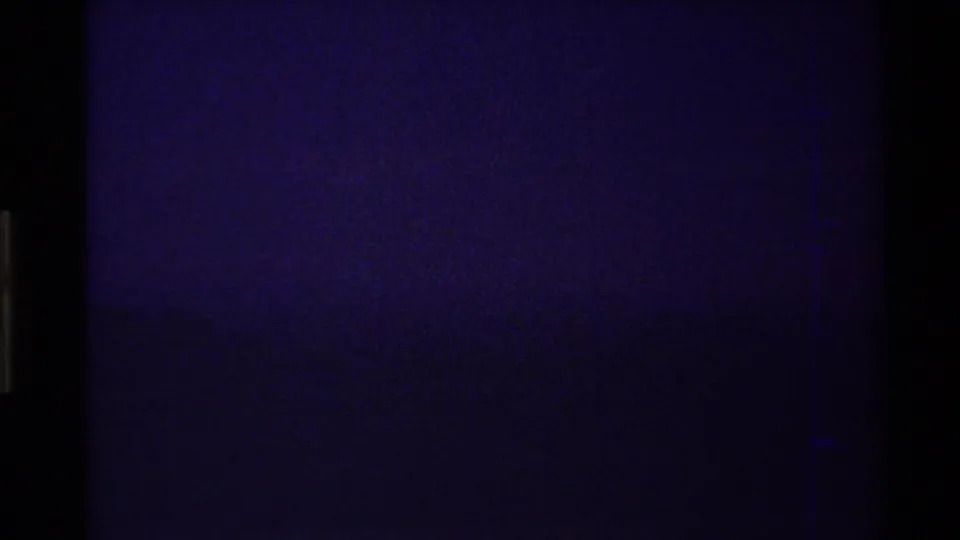 Opening 8mm frame from the supplied 1980 Western USA clip, nearly dark with faint blue-purple grain and visible film-edge artifacts.