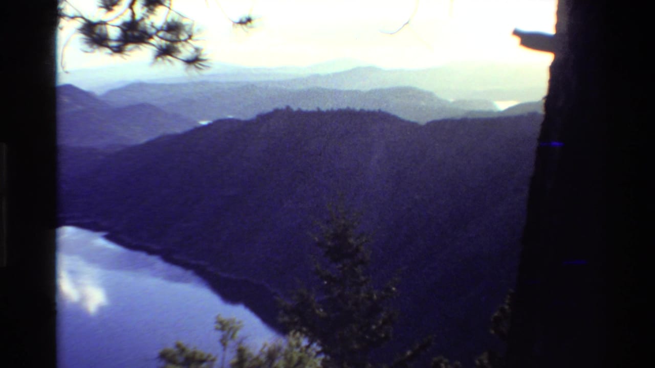 Mountain ridges and reflective water below a bright cloudy sky.