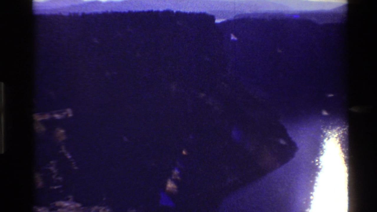 Reported 1980 Western USA 8mm frame showing the canyon in deep shadow and a bright late-day reflection on the river below.