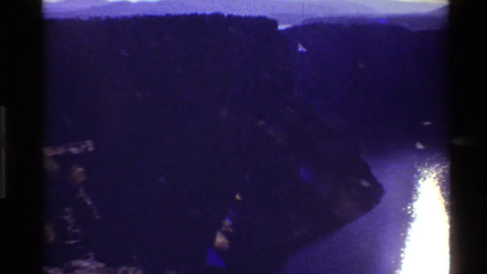 Reported 1980 Western USA 8mm frame showing the canyon in deep shadow and a bright late-day reflection on the river below.