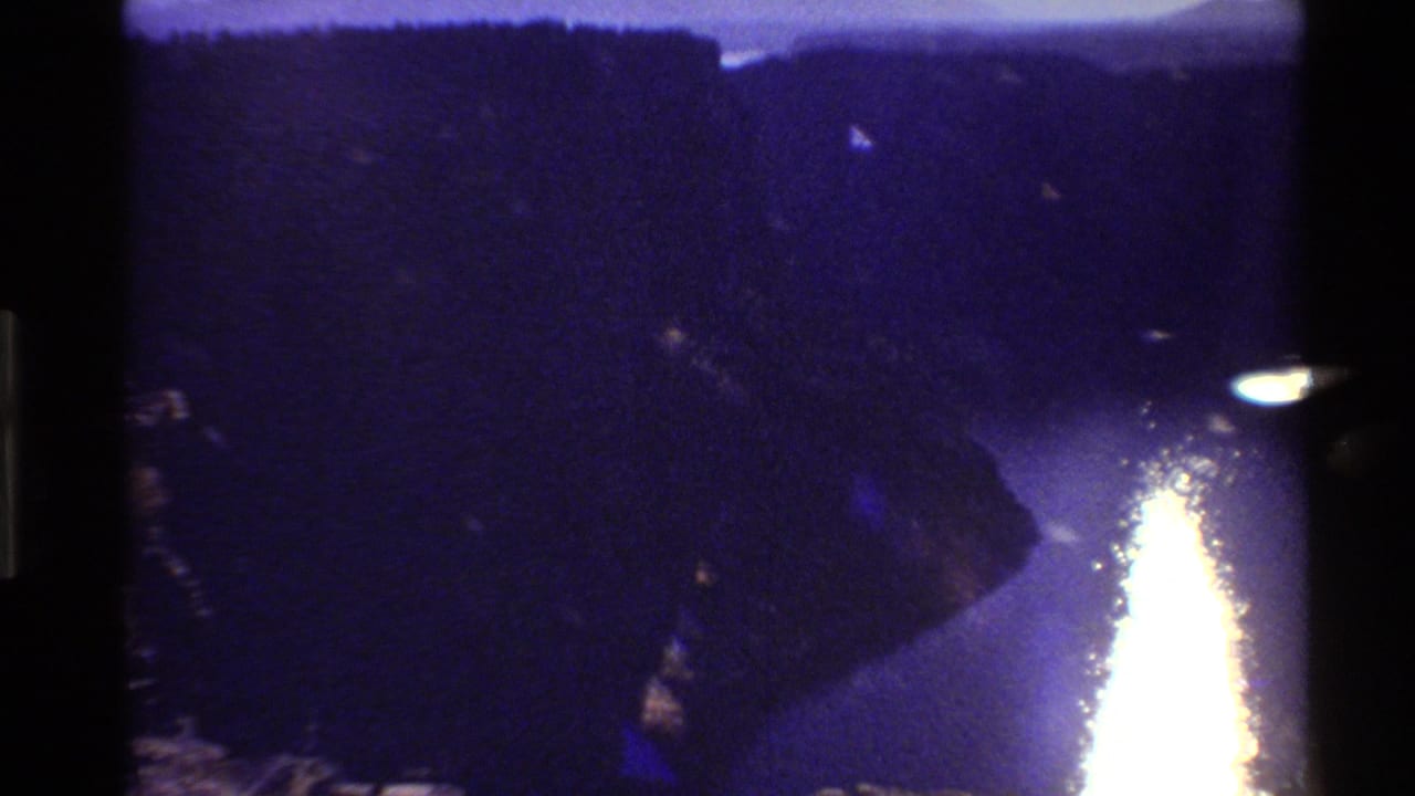 1980 Western U.S. 8mm frame showing a river reflecting sunset light between dark mountain or canyon walls.