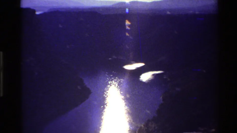 The 8mm frame shows a shadowed Western canyon river with strong sun reflection and distant mountain silhouettes.