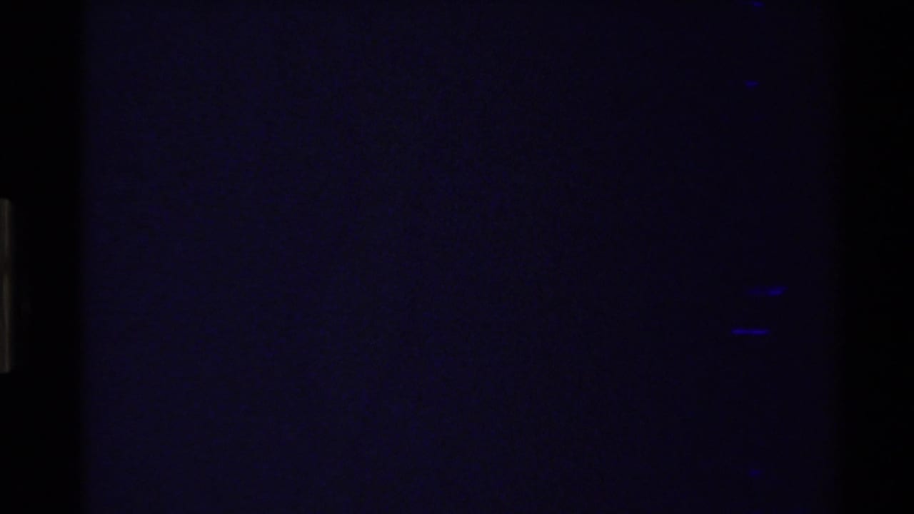 1980s 8mm frame beginning in darkness, with part of a blue river and pale canyon slopes visible in the upper right.