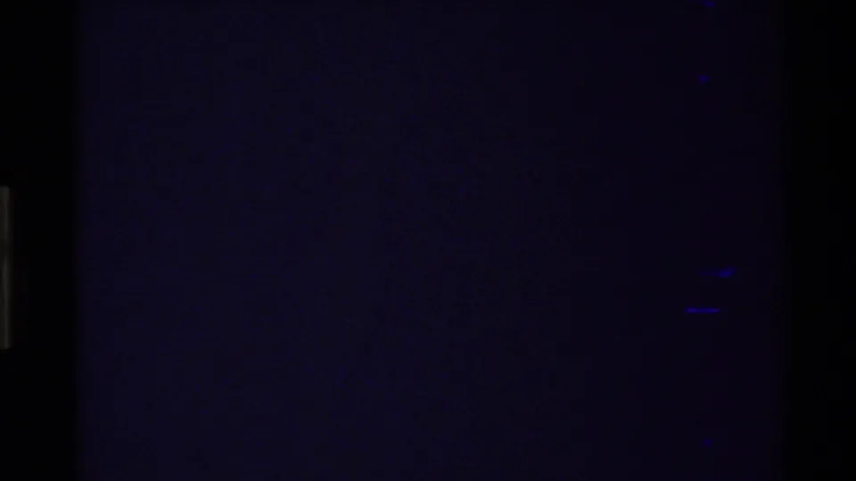 1980s 8mm frame beginning in darkness, with part of a blue river and pale canyon slopes visible in the upper right.