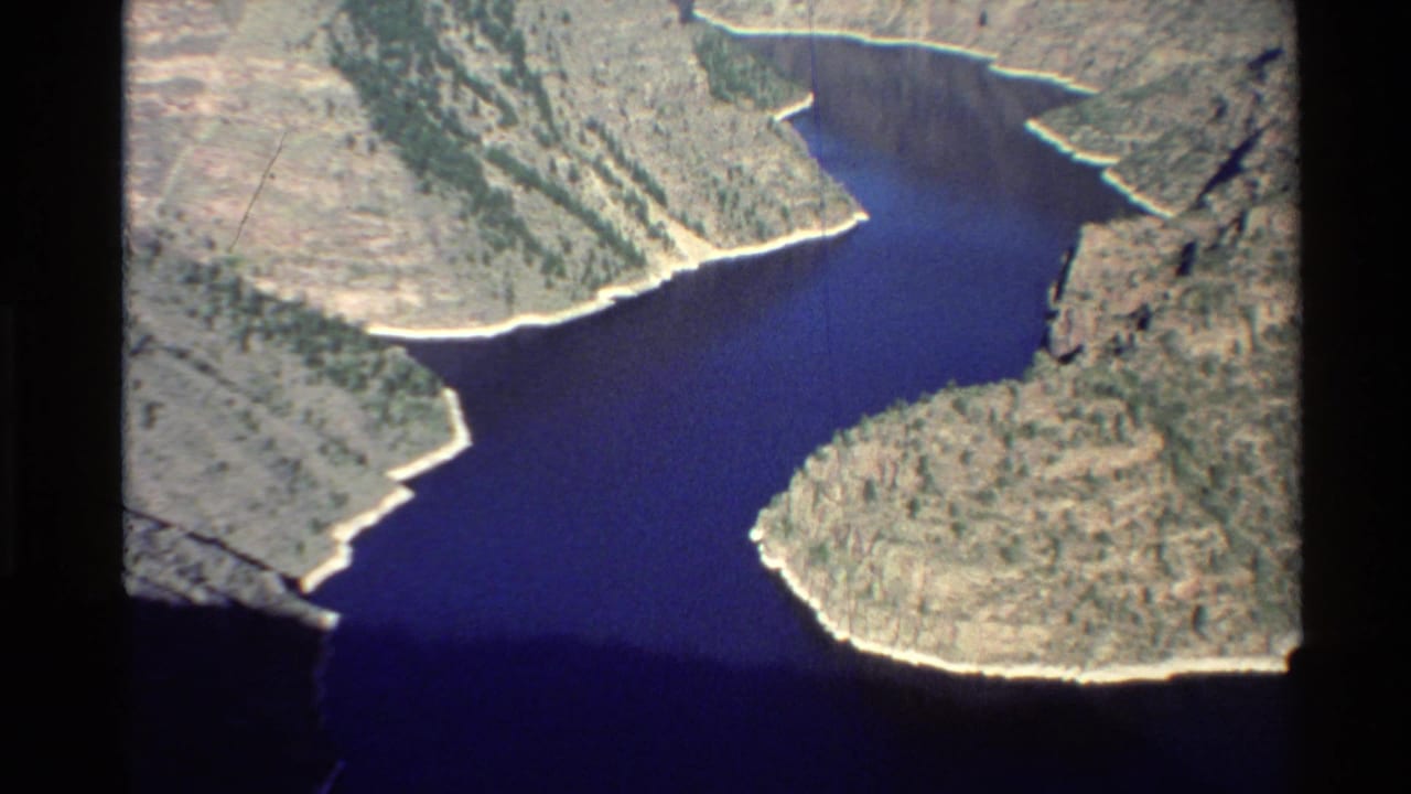 Aerial view of a deep blue river winding between pale canyon walls.
