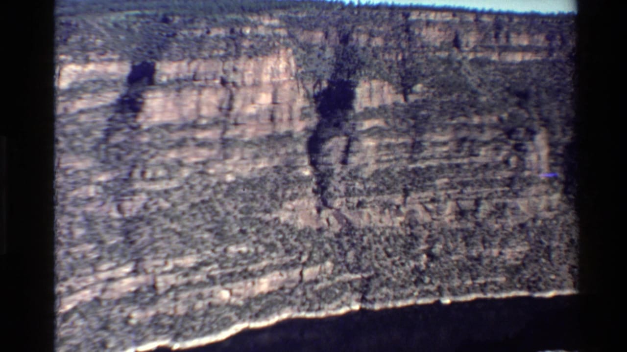 1980 Western U.S. 8mm frame showing layered canyon walls and a dark river or shadowed canyon floor below.