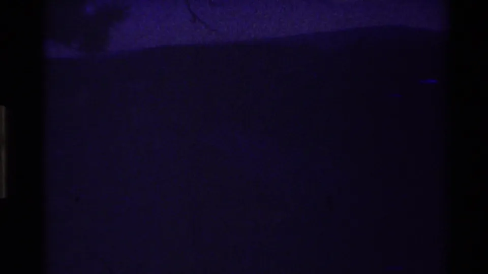Dark 8mm frame section, likely underexposed, unexposed, or damaged, with only faint blue-purple texture visible.