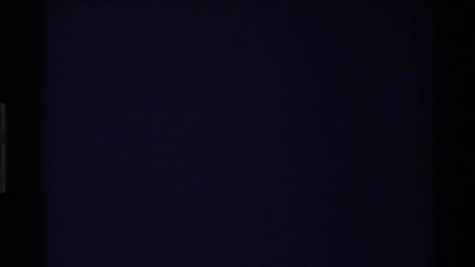 Dark 8mm transition frame with little visible subject detail and faint edge artifacts from the film scan.