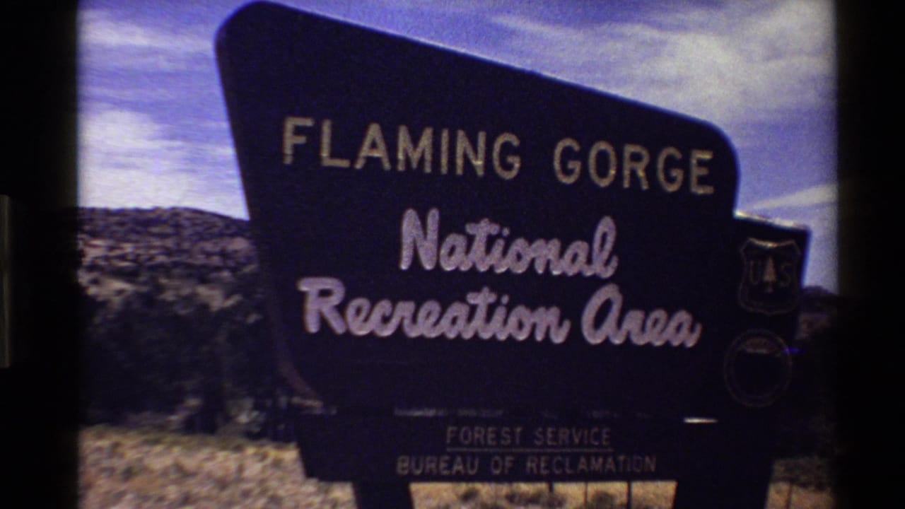 Flaming Gorge National Recreation Area sign partially visible against hills and sky.