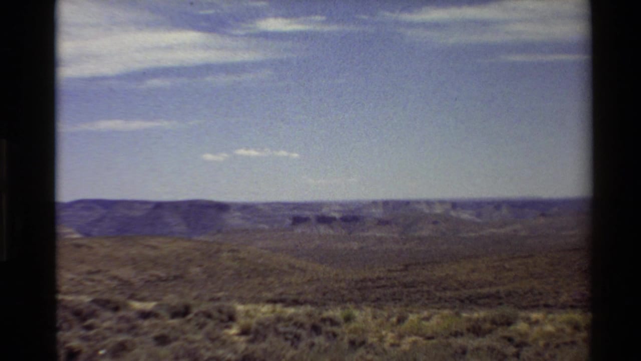 Handheld 8mm landscape frame showing dry hills and a broad canyon vista in the western United States, supported by the clip metadata.