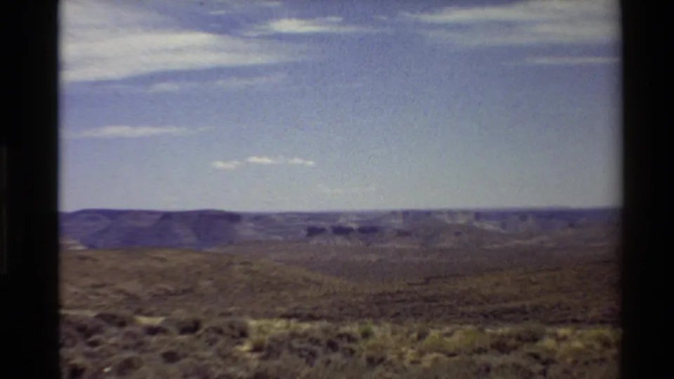 Handheld 8mm landscape frame showing dry hills and a broad canyon vista in the western United States, supported by the clip metadata.