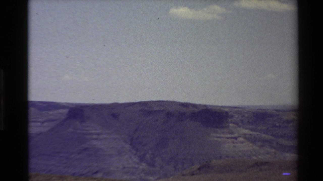 Western U.S. home-movie view from 1980 showing a ridgeline and canyon-like slopes beneath a bright open sky.