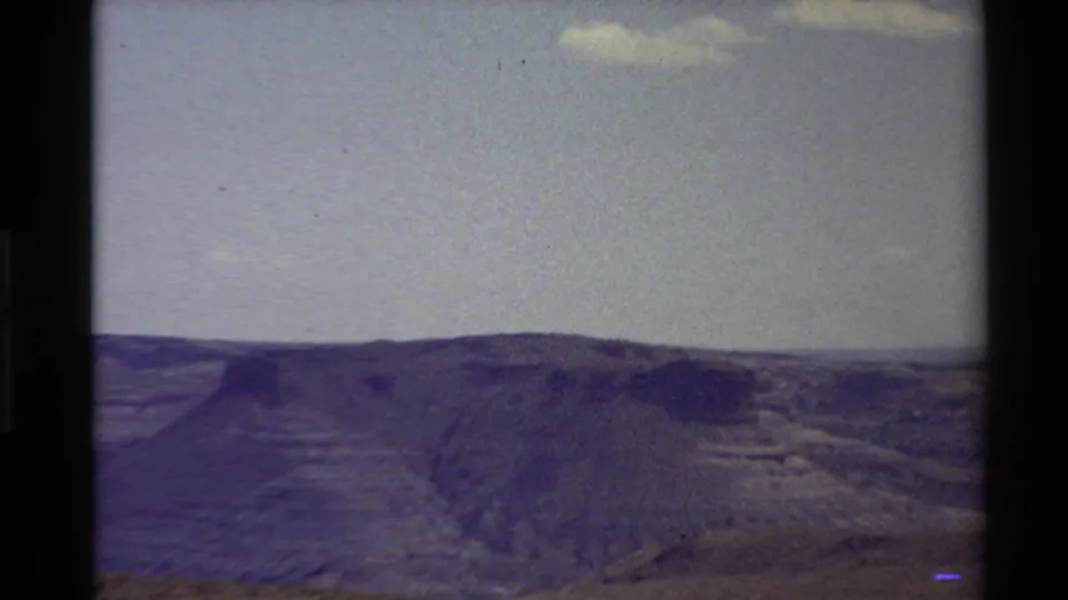Western U.S. home-movie view from 1980 showing a ridgeline and canyon-like slopes beneath a bright open sky.