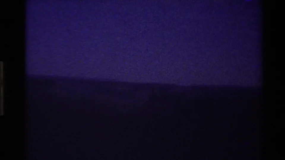 Underexposed 8mm view of a purple-toned sky and dark ridgeline in the Western USA, with film border visible.