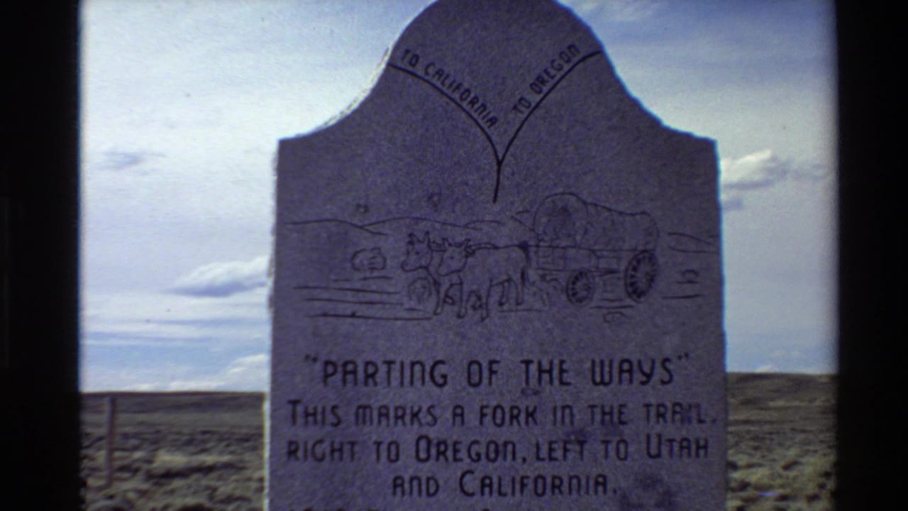 The marker is framed closer, showing the carved wagon scene and inscription about a fork in the trail toward Oregon, Utah, and California.