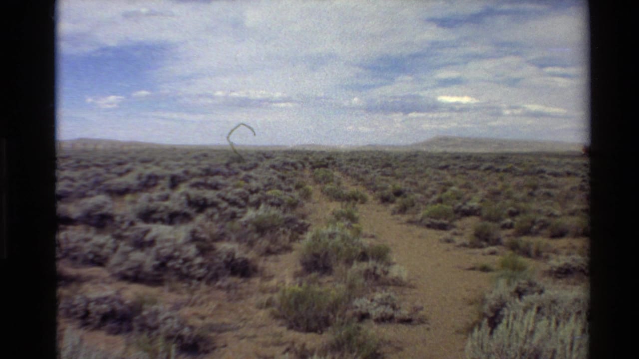 1980 8mm landscape frame showing a faint trail or dirt path through sagebrush on the Western USA plains.