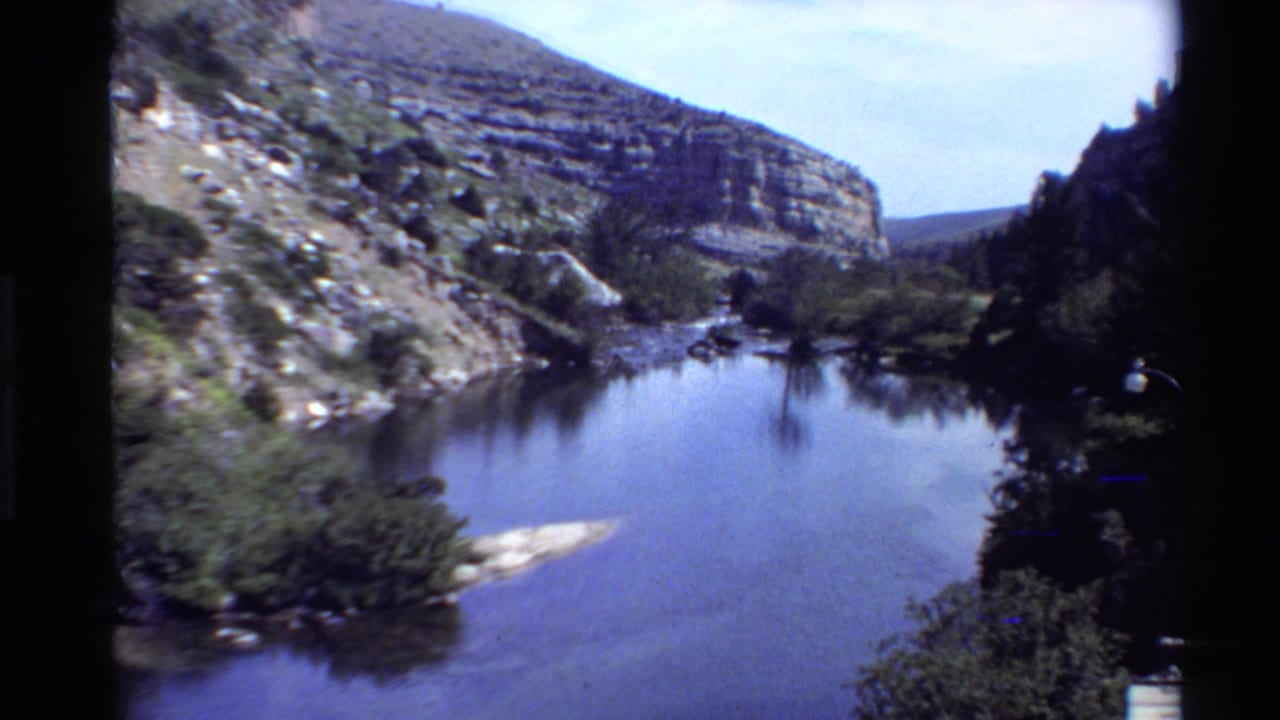 A wide 8mm view shows still canyon water, rocky hillsides, and trees in a Western U.S. landscape.