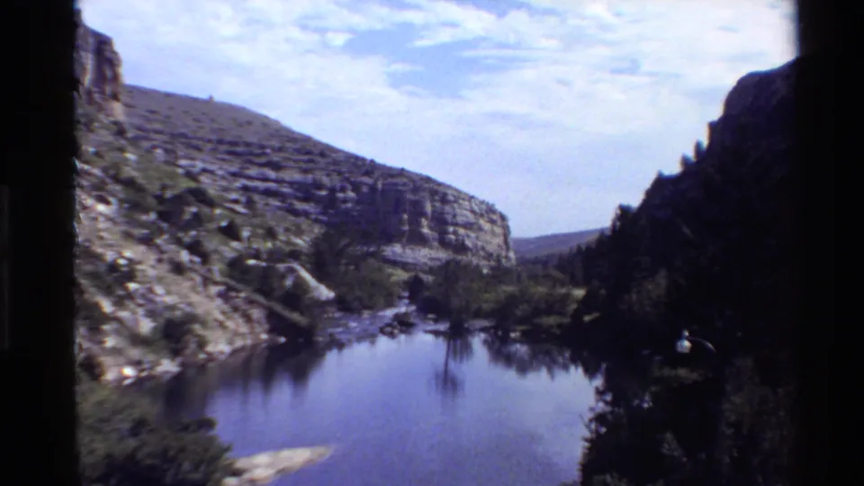Wide 8mm view of still water, steep rock formations, and trees in a Western U.S. canyon setting.