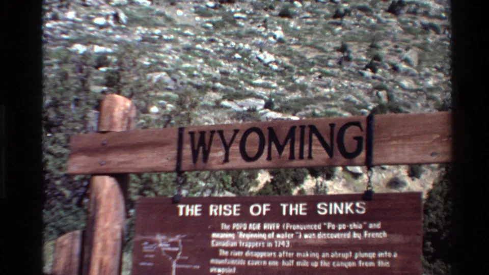 1980 8mm frame with rustic Wyoming lettering and a partly readable The Rise of the Sinks sign below it.