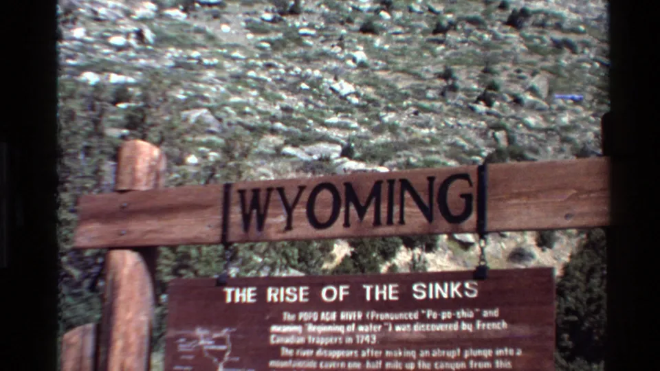 1980 8mm home-movie frame showing the Wyoming sign and The Rise of the Sinks plaque from a slightly lower handheld angle.