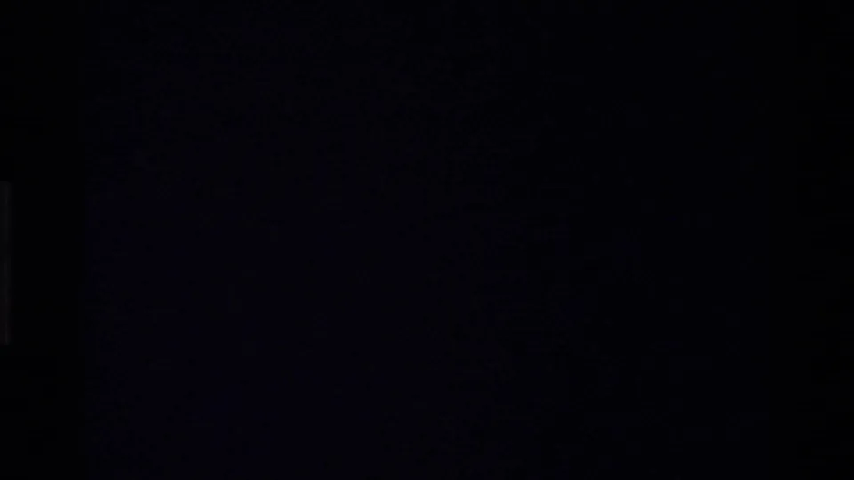 Mostly black 8mm transition frame with only faint edge detail visible between the wayside view and storm footage.