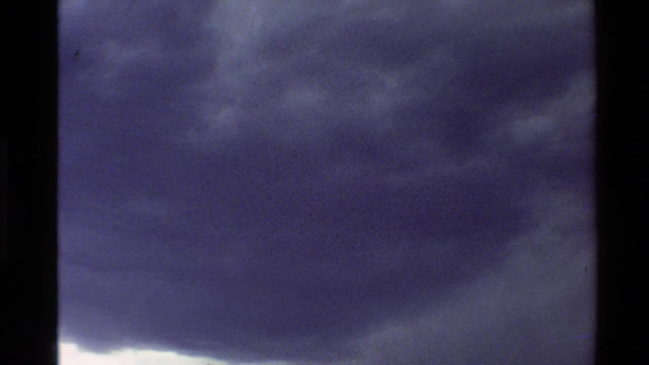 8mm home-movie view of a dense storm cloud moving across a mountain horizon in the Western U.S.